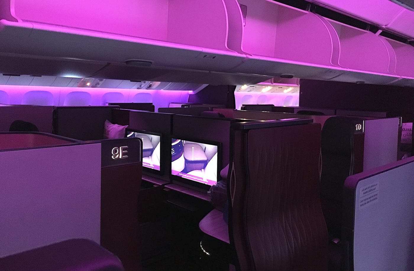 Qatar Airways QSuite cabin on a Boeing 777 with signature purple mood lighting